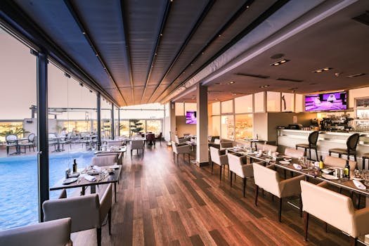 Spacious modern restaurant interior with a poolside view, featuring elegant furniture and contemporary design.